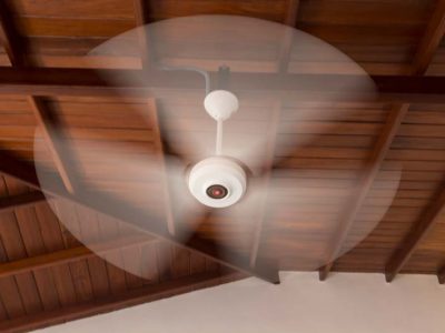 close up centered shot of a rotating white electric plastic ceiling fan on a wooden ceiling